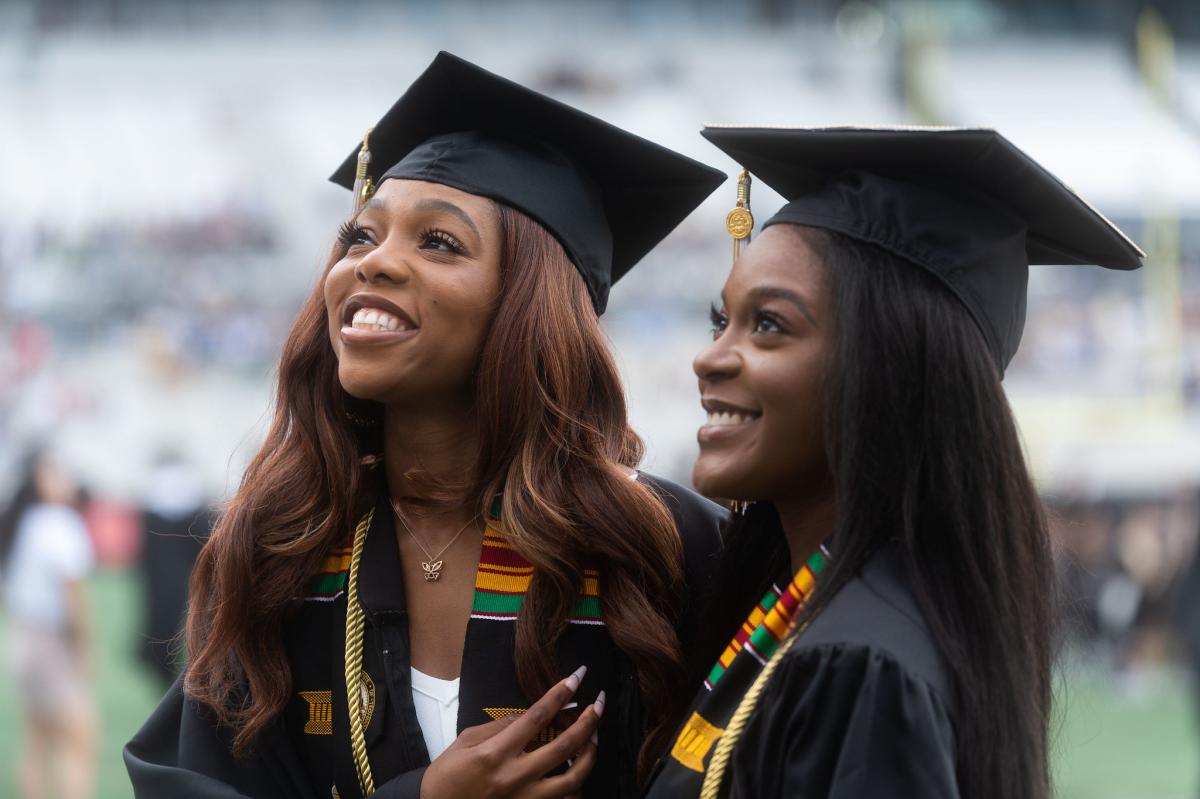 Two women looking at the crowd at graduation.